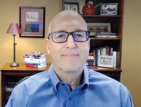 Matt De Pretis wearing glasses and a blue shirt in an office.